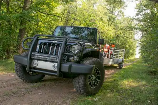 Jeep towing a trailer carrying a dirt bike